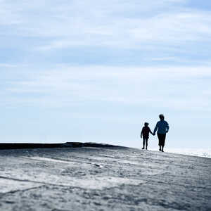 Two people walk hand in hand across the Cobb in Lyme Regis
