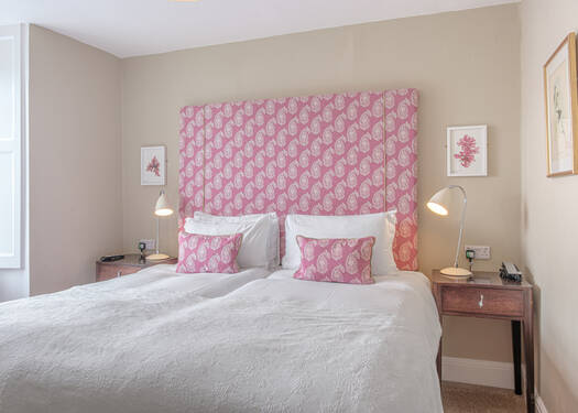 Cozy bedroom with a pink patterned headboard and matching pillows, two nightstands.