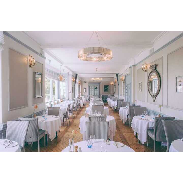 Elegant restaurant interior with white tablecloths, modern decor, and large windows.