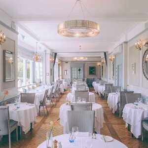 Elegant restaurant interior with white tablecloths, modern decor, and large windows.