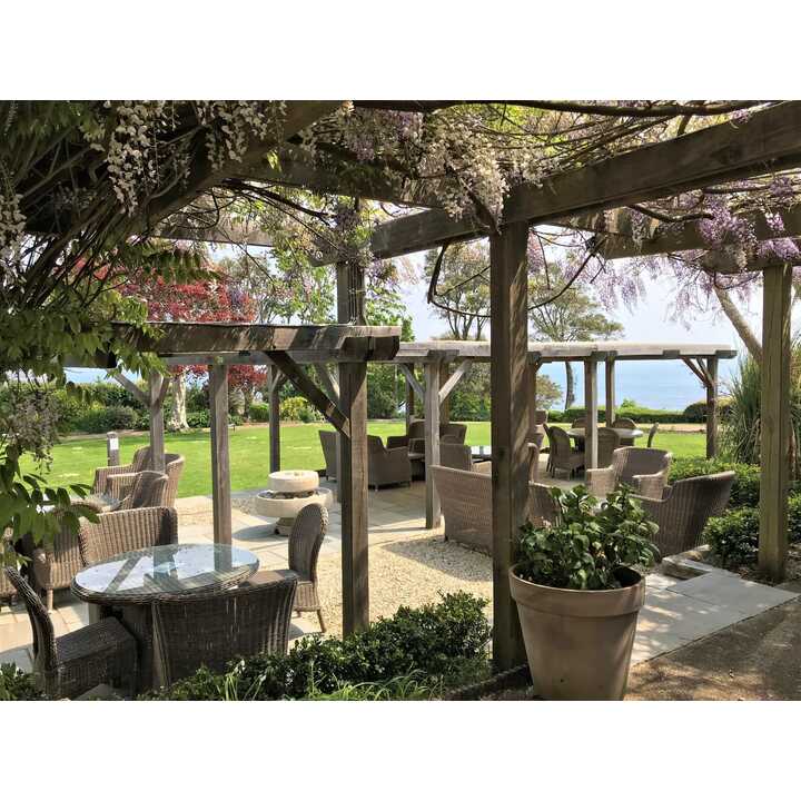 Outdoor seating area with wicker chairs, tables, and a view of the ocean.