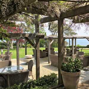 Outdoor seating area with wicker chairs, tables, and a view of the ocean.