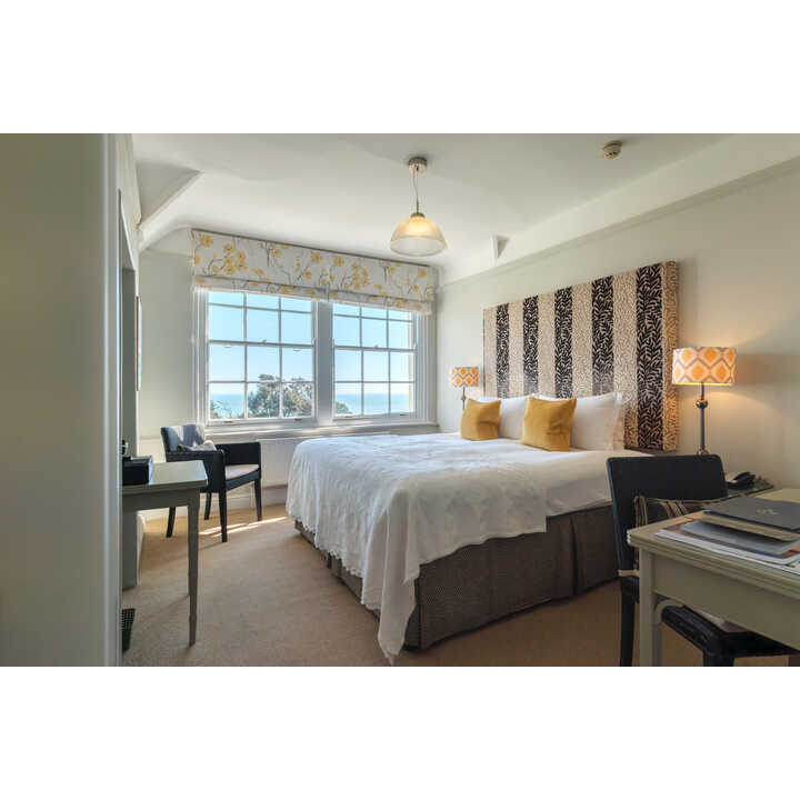 A cozy bedroom with a large bed, two lamps, and ocean view windows.