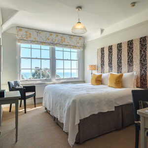 A cozy bedroom with a large bed, two lamps, and ocean view windows.
